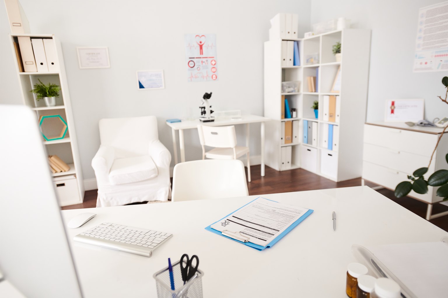 Consulta médica luminosa con escritorio, sillón y estanterías en una clínica moderna