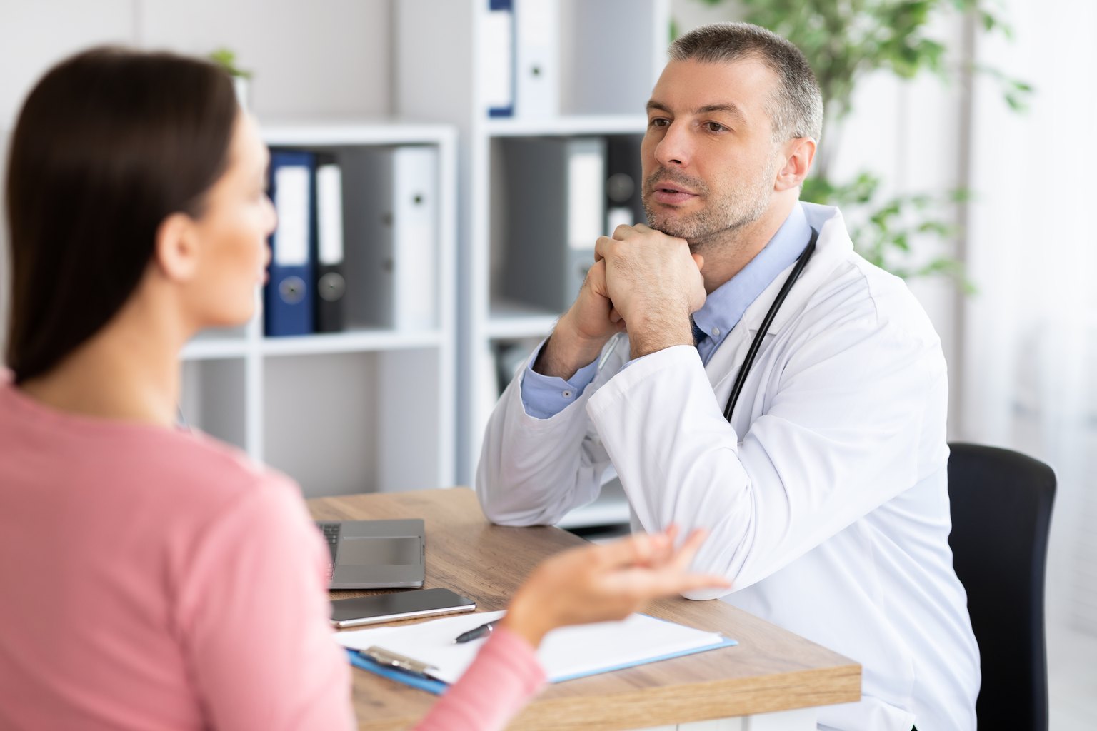Médico escuchando con atención a una paciente durante la consulta
