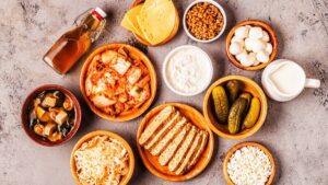 Alimentos fermentados vistos desde arriba: kimchi, chucrut, yogur, kéfir, tempeh, sopa de miso, queso, pepinillos y kombucha
