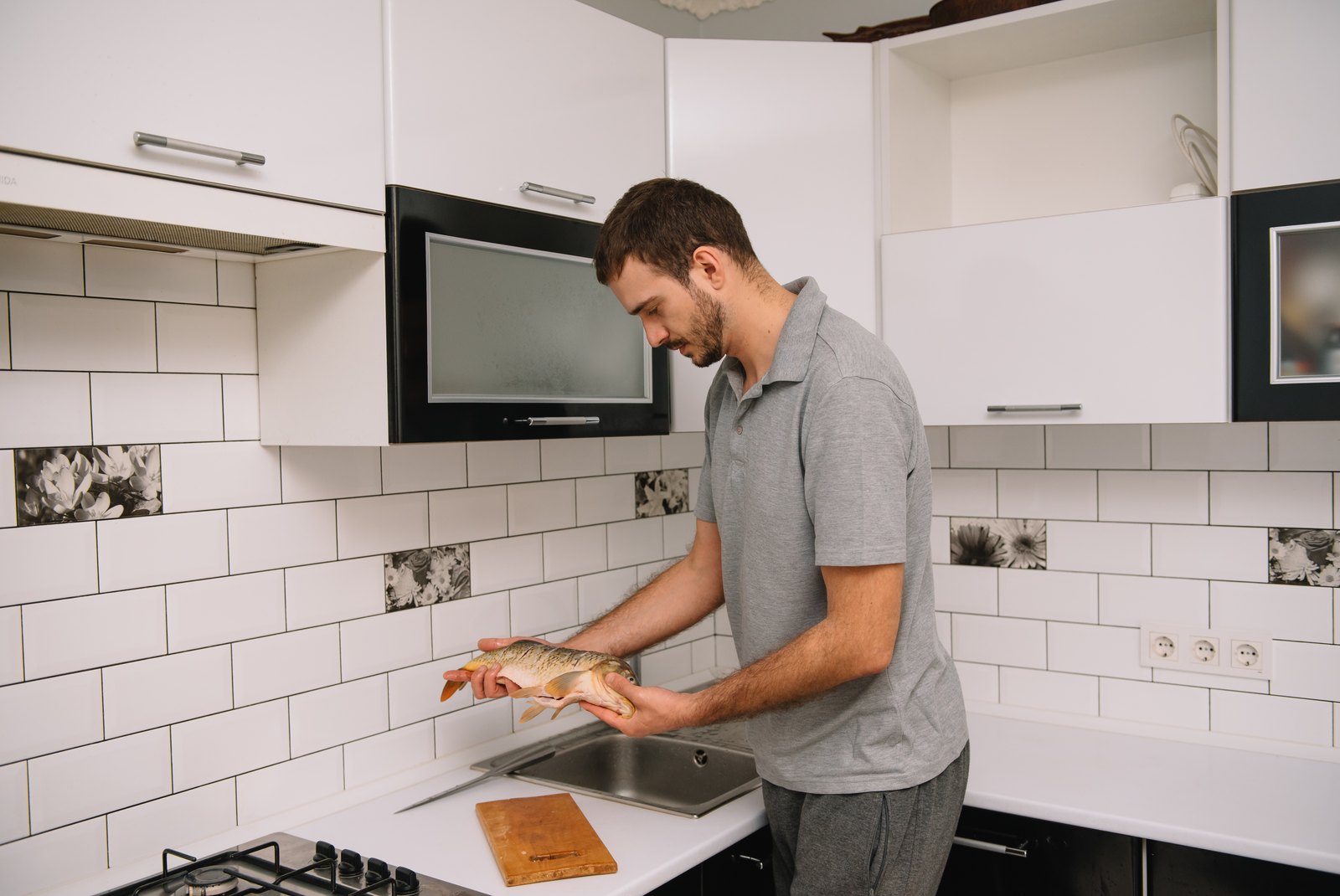 Hombre preparando pescado fresco en la cocina de su casa