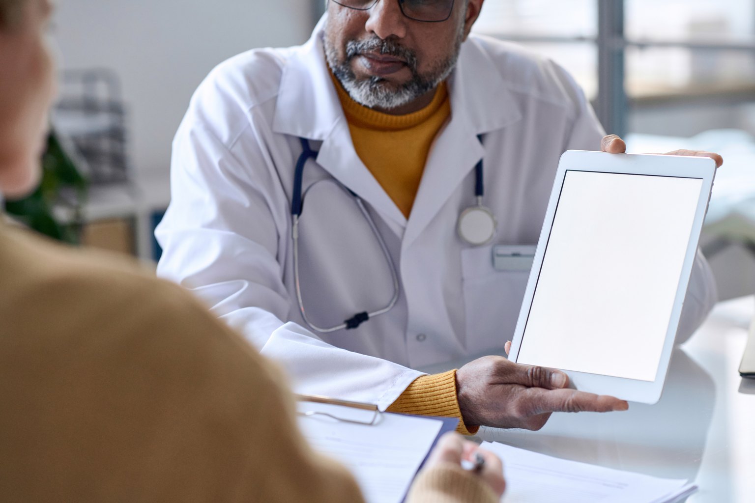 Médico mostrando en una tableta el plan de salud a un paciente durante la consulta
