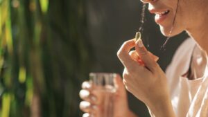 Mujer tomando una cápsula de vitamina con un vaso de agua